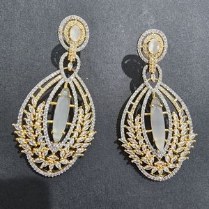 Silver and gold earrings with white stone in middle
